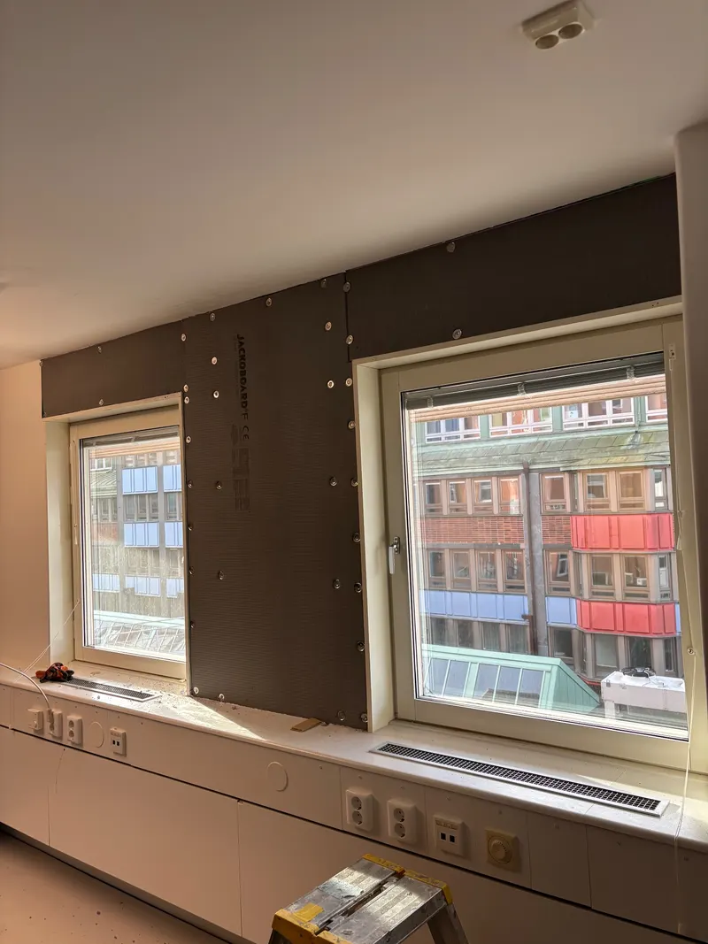 Vägg med mörka skivor runt nya fönster under renovering